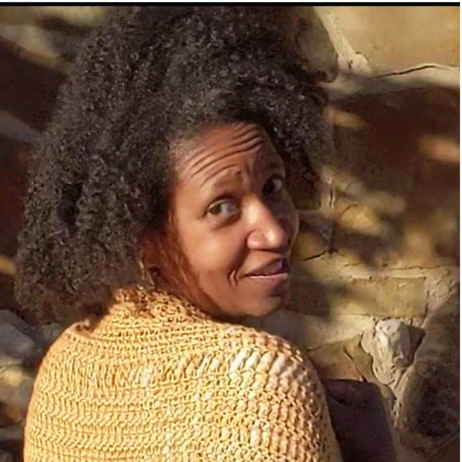 A closeup headshot photo of the Author, Ro Cain, looking back over her shoulder at the camera